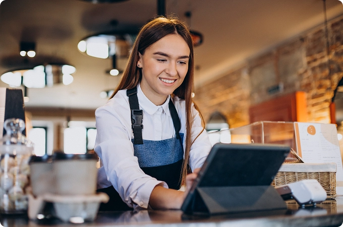 Barista femenina con tableta haciendo pedidos en una cafetería