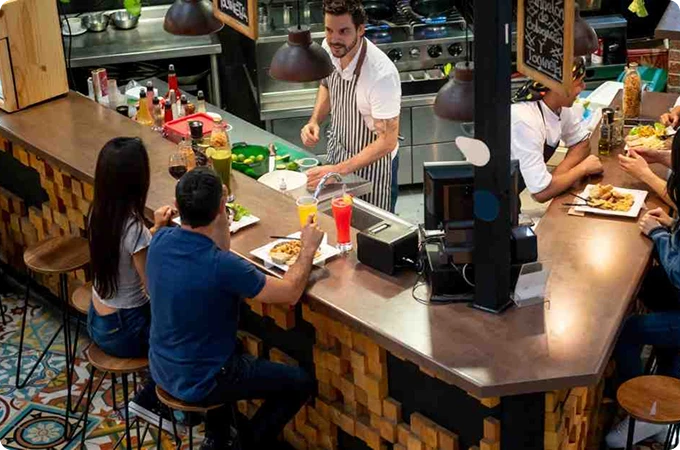 barra restaurante con garzon y personas comiendo