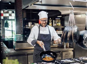 chef en dark kitchen cocinando con una sarten